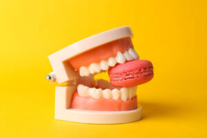 Human jaw model with french macaroons on yellow background