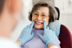 Happy senior woman sitting in dental chair, dentist looking at teeth after treatment, whitening